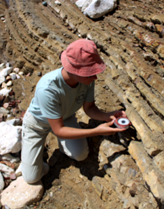 Une géologue utilise une boussole pour mesurer l’inclinaison des couches de roche. Une géologue utilise une boussole pour mesurer l’inclinaison des couches de roche.